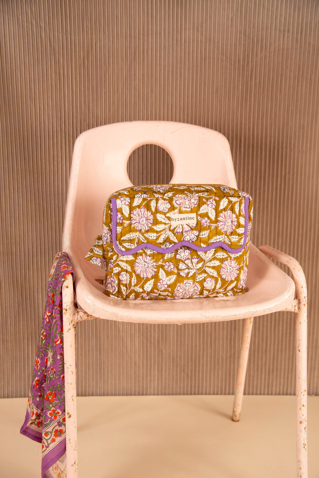 Trousse rabat Carthage Kaki à bord festonné violet, sur une chaise rose avec un foulard