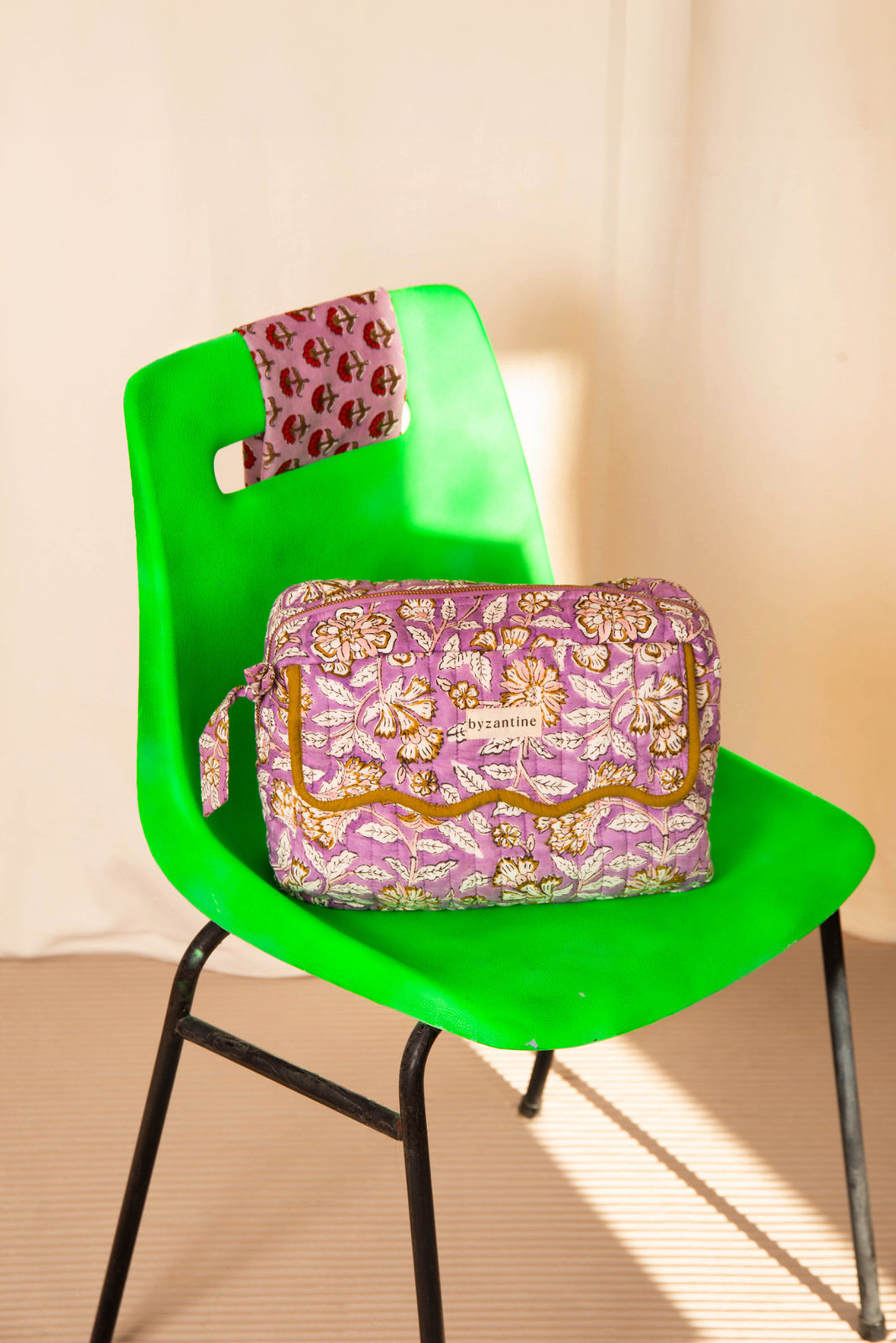 Trousse rabat Carthage Lilas à bord festonné moutarde, posée sur une chaise vert vif