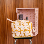 Trousse rabat Fauve Rose à bord festonné moutarde, avec flacons, sur un tabouret