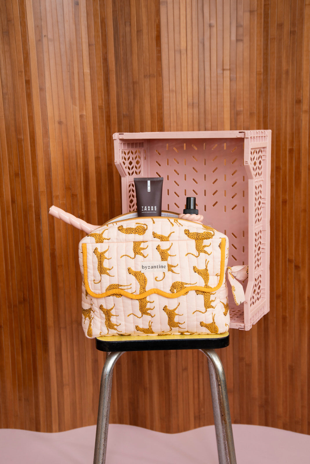 Trousse rabat Fauve Rose à bord festonné moutarde, avec flacons, sur un tabouret