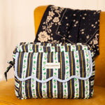 Trousse rabat Flora Bleu marine à bord festonné bleu ciel, sur un fauteuil moutarde