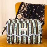 Trousse rabat Flora Bleu marine à bord festonné bleu ciel, sur un fauteuil moutarde