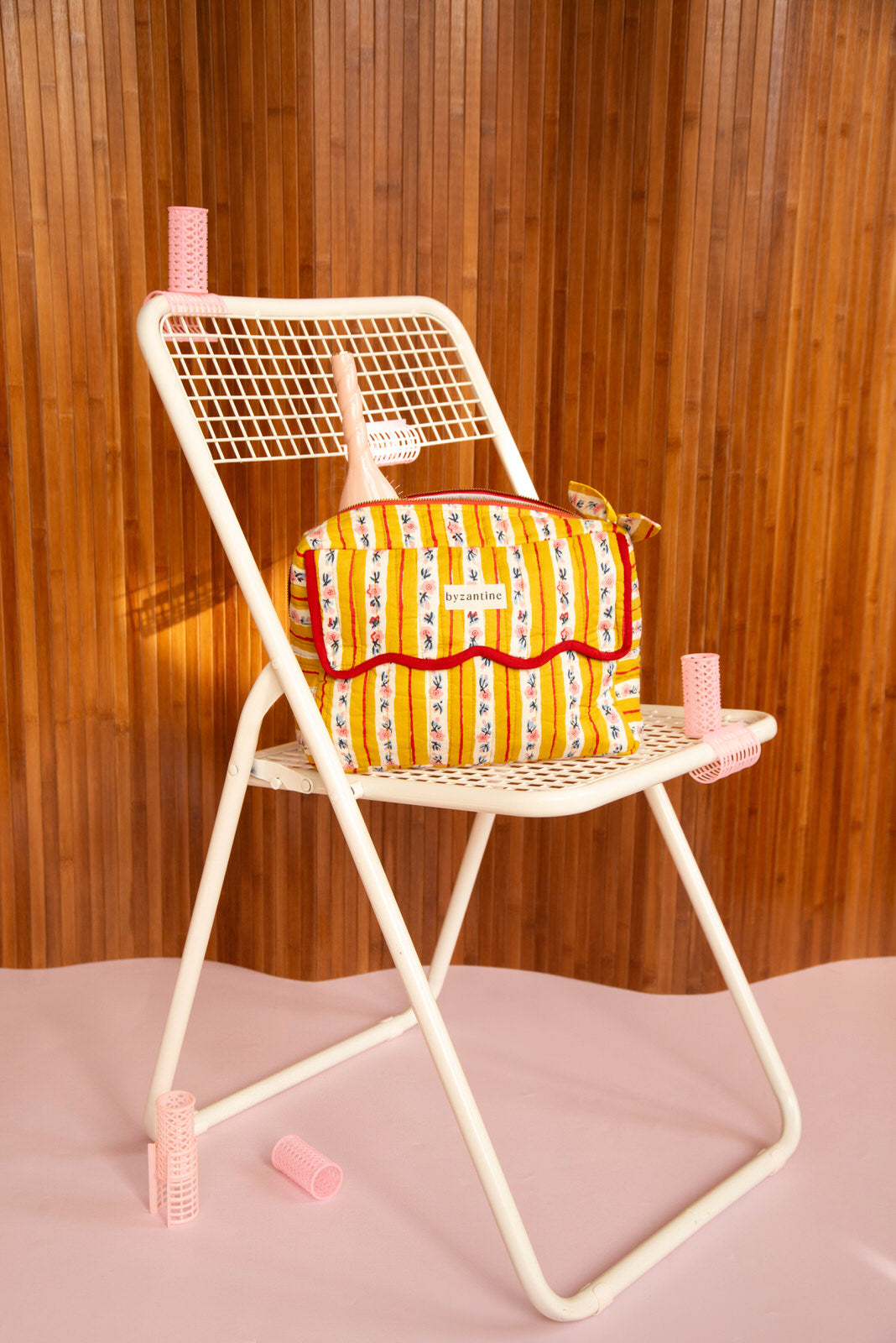 Trousse rabat Flora Passion à bord festonné rouge, posée sur une chaise pliante blanche