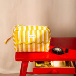 Trousse rabat Pacha Passion à bord festonné, posée sur une table rouge