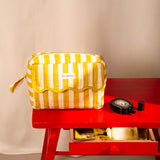 Trousse rabat Pacha Passion à bord festonné, posée sur une table rouge