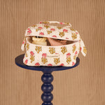 Trousse vanity N°50 Rose ouverte sur un guéridon bleu marine