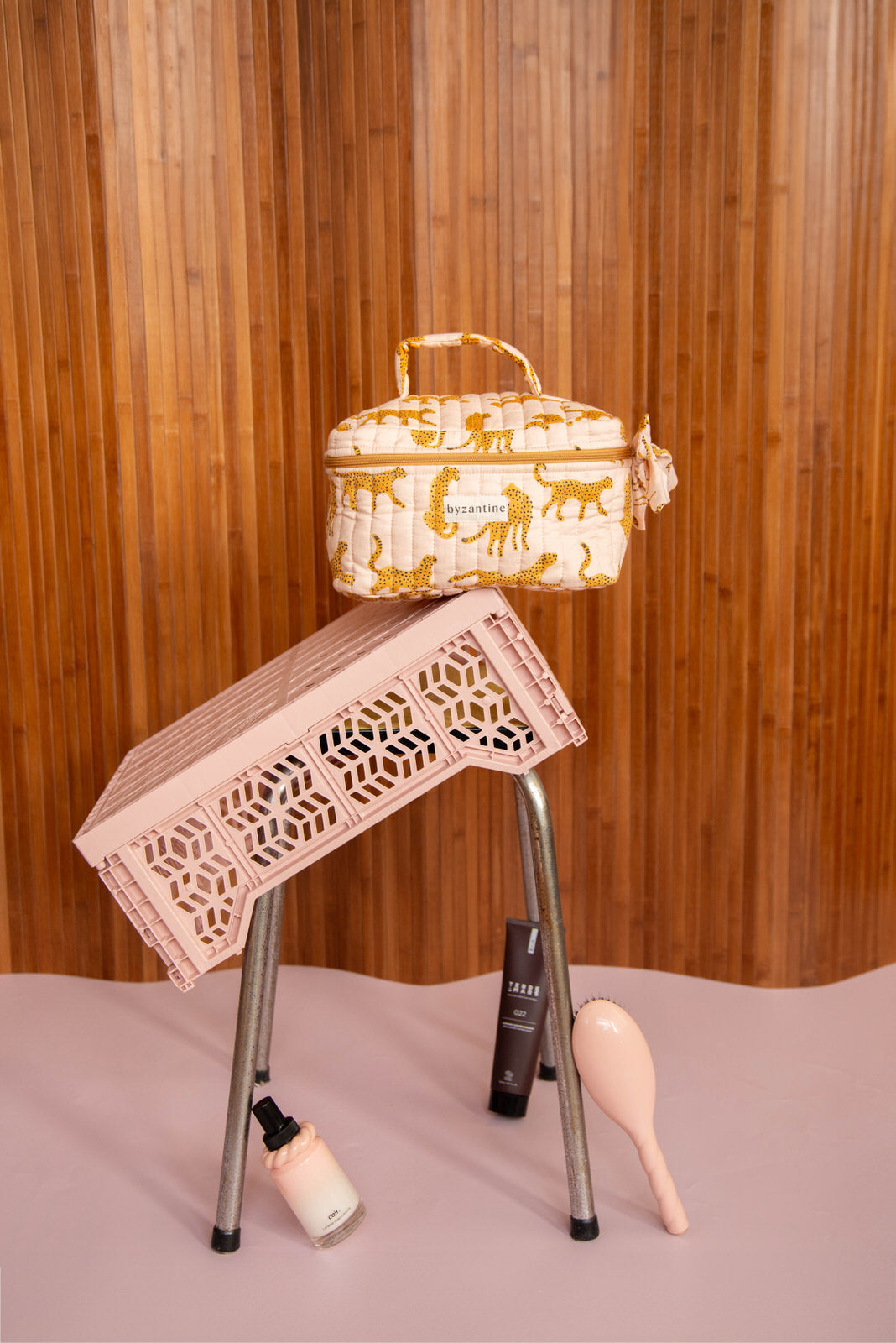 Trousse vanity Fauve Rose sur une caisse rose renversée, soins posés au sol