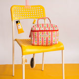 Trousse vanity Flora Rose de Byzantine sur une chaise jaune, avec une crème