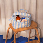 Trousse vanity Pacha Bleu ciel ouverte, remplie de soins, sur un escabeau