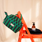 Trousse vanity Pacha Menthe suspendue au dossier d'une chaise orange
