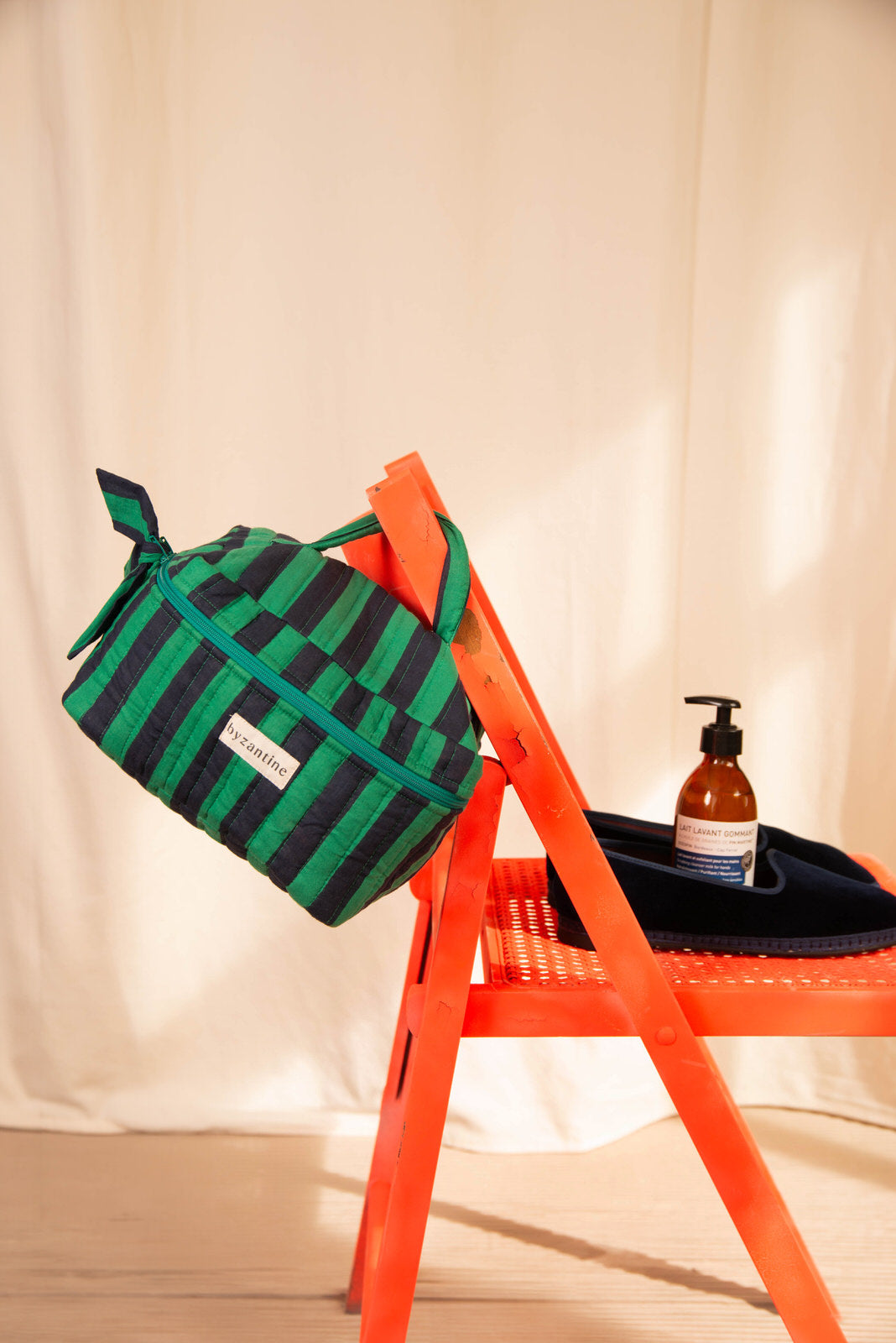 Trousse vanity Pacha Menthe suspendue au dossier d'une chaise orange