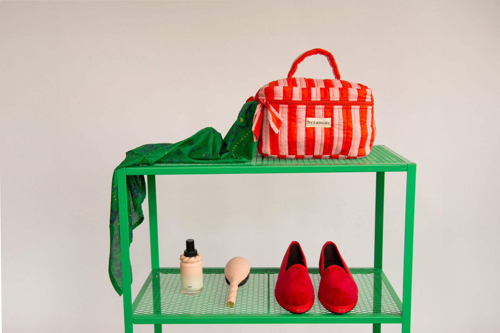 Trousse vanity Pacha Tomato à poignée, rayures rouge et rose, sur une étagère verte