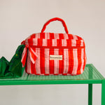 Gros plan sur la trousse vanity Pacha Tomato de Byzantine, poignée et nœud rayés