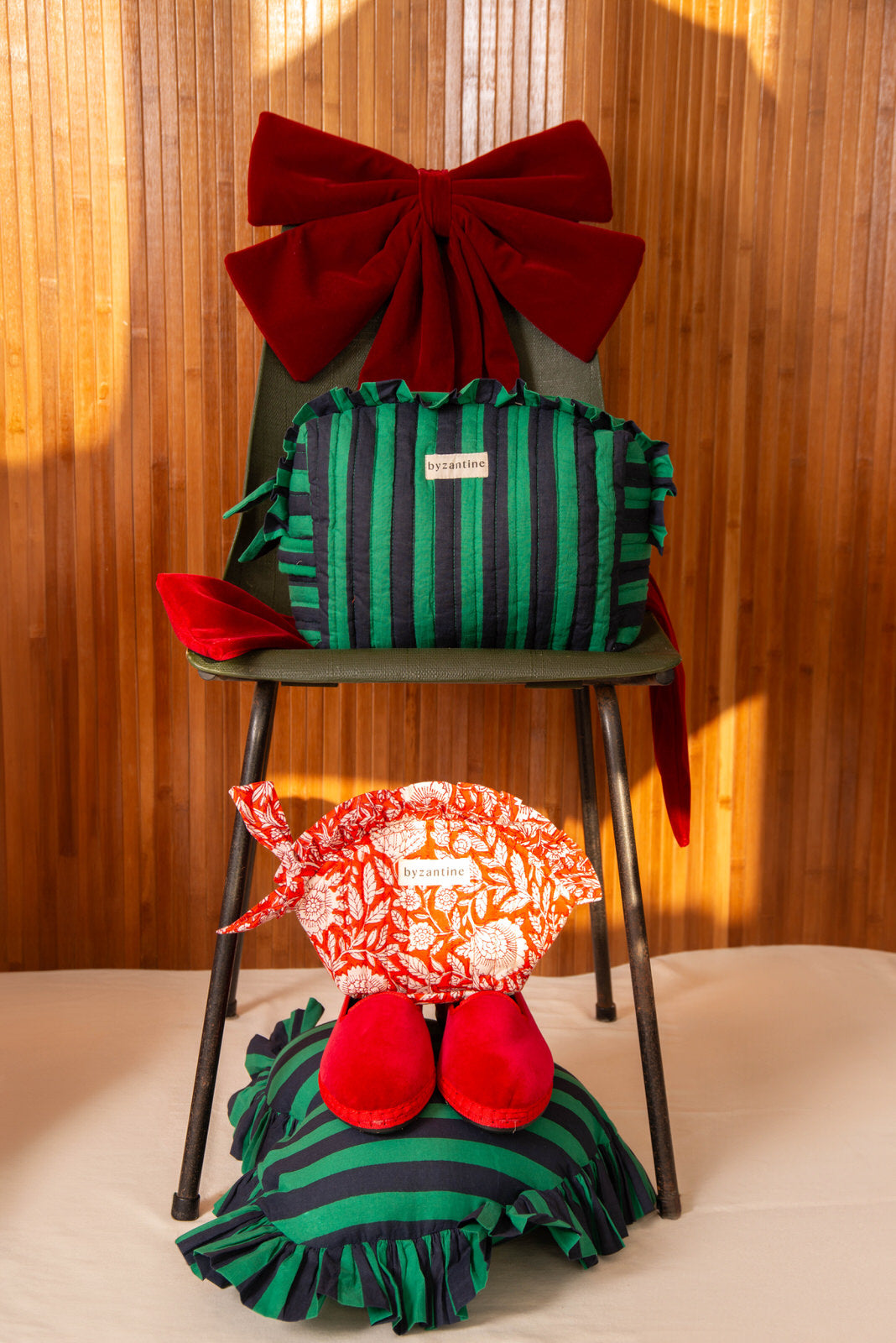Mise en scène de Noël Byzantine : trousses Pacha Menthe et Antioche Tomato sous un grand nœud rouge