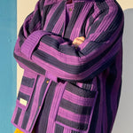 Veste matelassée Joseph portée bras croisés, larges rayures violet et bleu nuit, poches plaquées