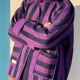 Veste matelassée Joseph portée bras croisés, larges rayures violet et bleu nuit, poches plaquées