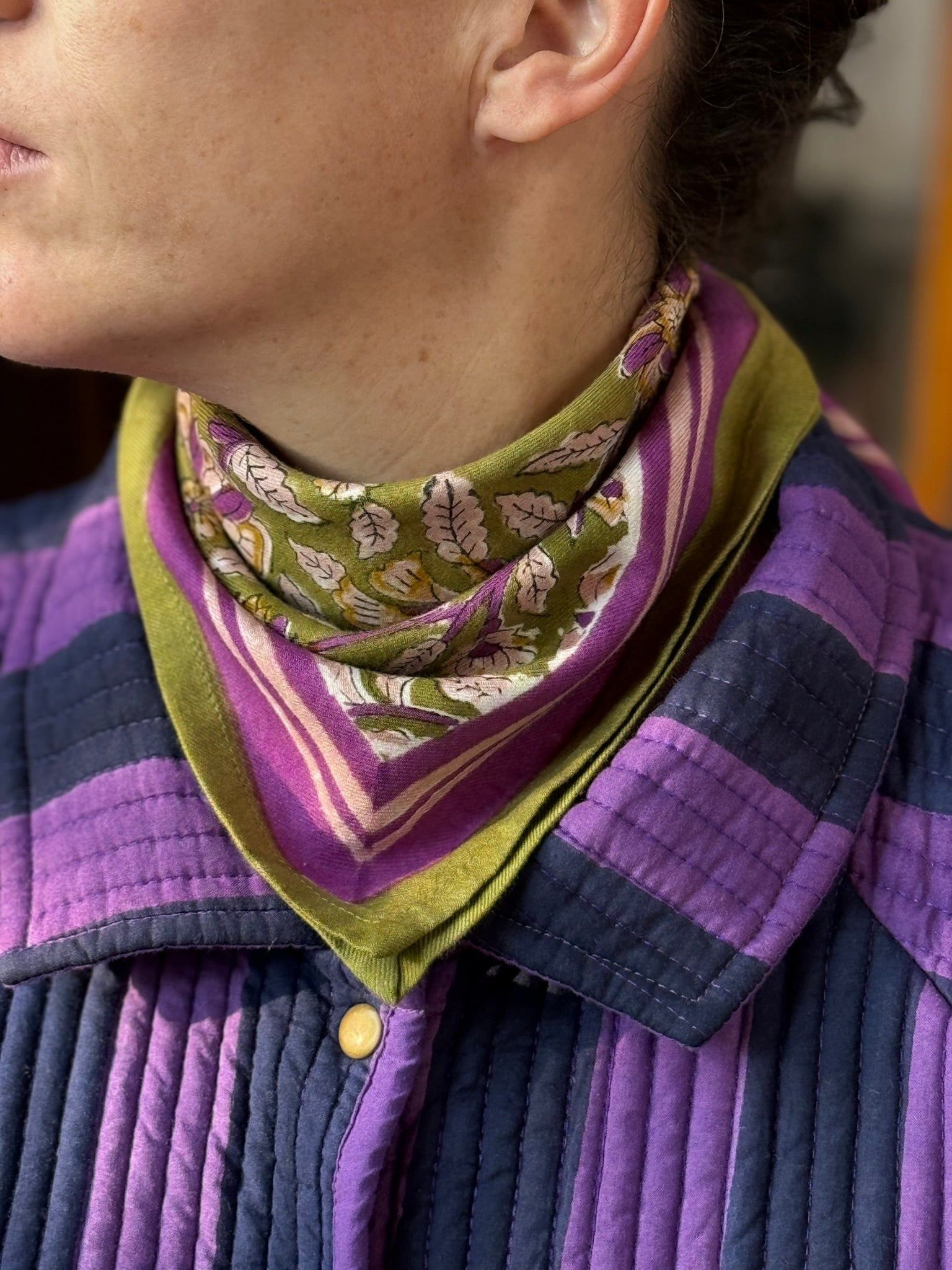 Détail du col chemise de la veste Joseph rayée, portée avec un petit foulard vert noué au cou