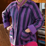 Veste matelassée Joseph rayée bleu et violet portée ouverte avec un foulard et un pantalon rose