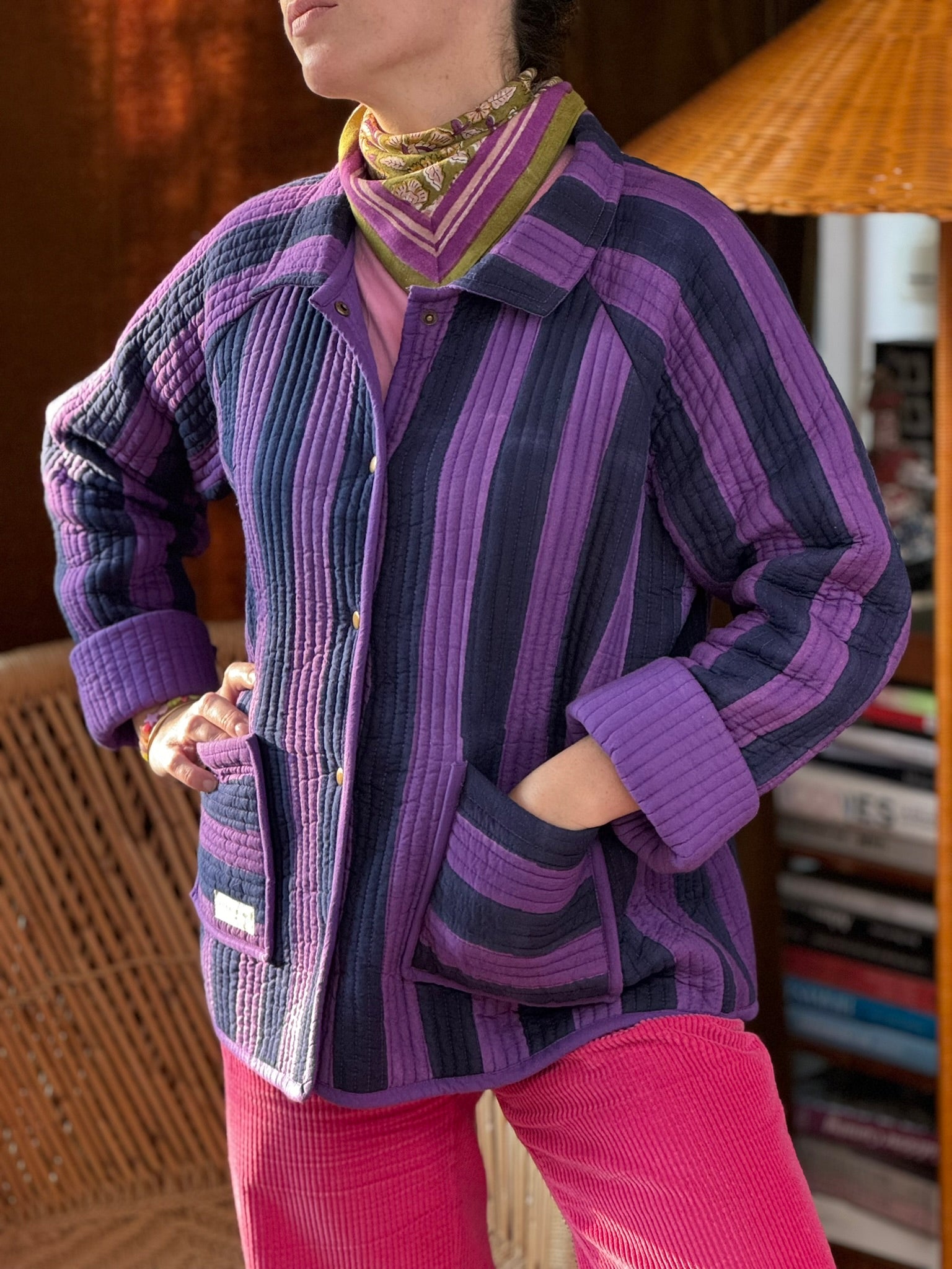 Veste matelassée Joseph rayée bleu et violet portée ouverte avec un foulard et un pantalon rose